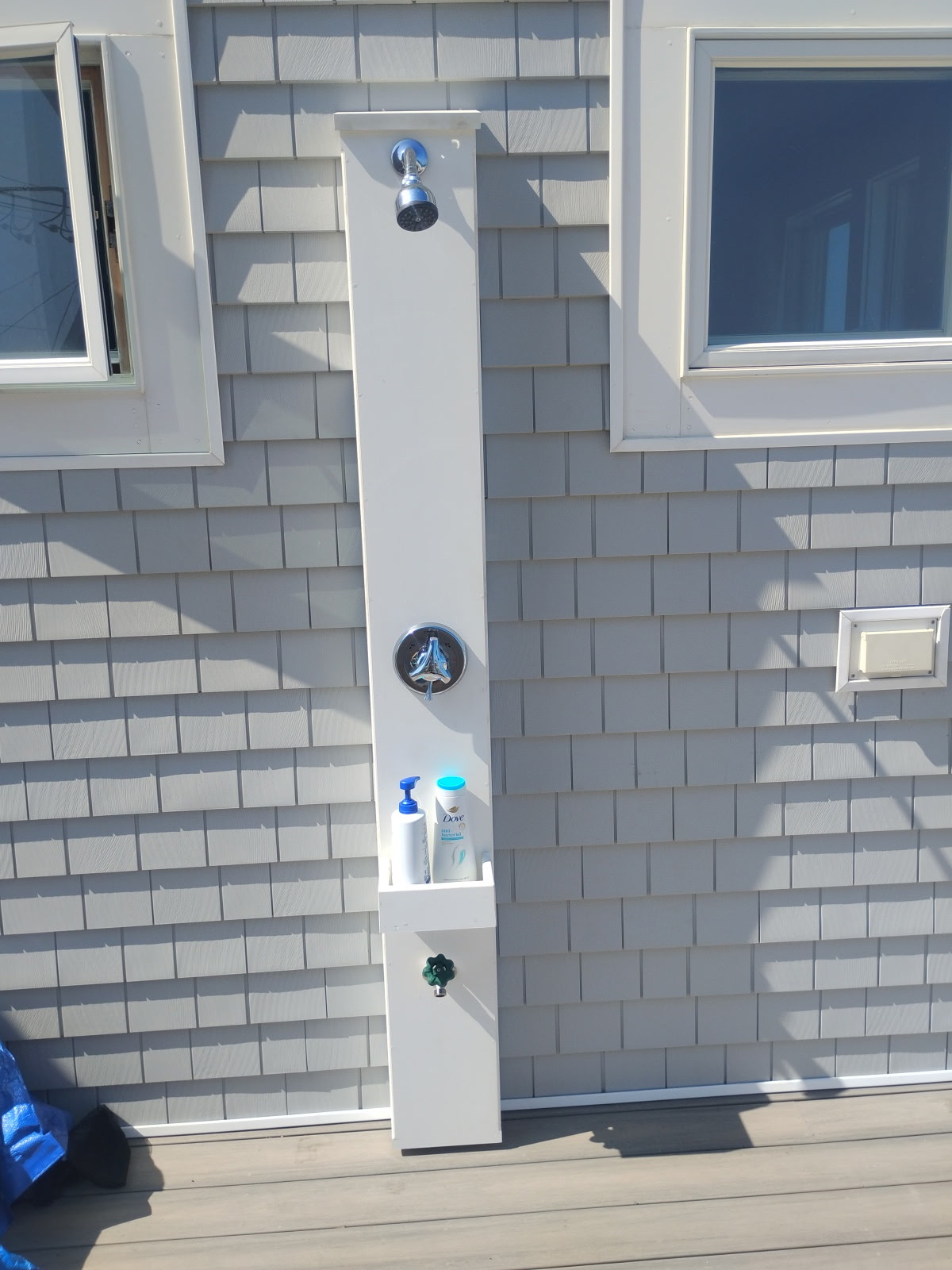 Outdoor shower installation on a cedar-shingle home